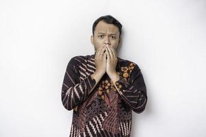 Shocked Indonesian man wearing batik shirt and looking up, isolated by white background photo