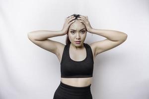 A portrait of an sporty Asian woman wearing a sportswear isolated by white background looks depressed photo