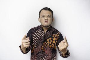 The angry and mad face of Asian man in batik shirt isolated white background. photo