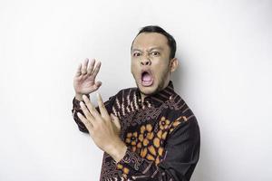 The angry and mad face of Asian man in batik shirt isolated white background. photo