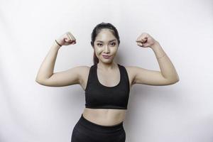 Excited Asian sporty woman wearing a sportswear showing strong gesture by lifting her arms and muscles smiling proudly photo