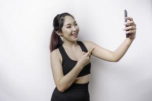 A portrait of a sporty Asian woman wearing a sportswear and holding her phone, isolated by white background photo