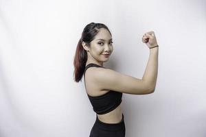 Excited Asian sporty woman wearing a sportswear showing strong gesture by lifting her arms and muscles smiling proudly photo