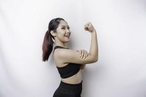 Excited Asian sporty woman wearing a sportswear showing strong gesture by lifting her arms and muscles smiling proudly photo