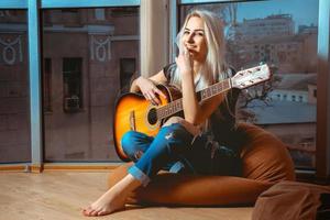 joyful young blonde girl plays guitar photo