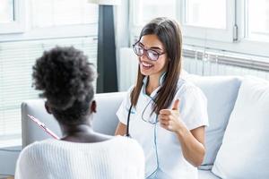 Doctor and patient discussing something while sitting at the table . Medicine and health care concept. Beautiful young female doctor giving thumbs up photo