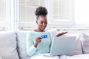 Confused young woman having problem with blocked credit card making rejected unsecure online payment using laptop at home, invalid expired account, transaction failed, money withdraw impossible, debt photo