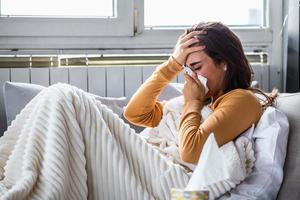 Cold And Flu. Portrait Of Ill Woman Caught Cold, Feeling Sick And Sneezing In Paper Wipe. Closeup Of Beautiful Unhealthy Girl Covered In Blanket Wiping Nose. Healthcare Concept. photo