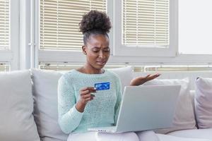 Confused young woman having problem with blocked credit card making rejected unsecure online payment using laptop at home, invalid expired account, transaction failed, money withdraw impossible, debt photo