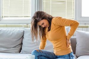 dolor de espalda. primer plano de una mujer joven que tiene dolor espinal o renal, dolor de espalda. niña que sufre de sensación dolorosa, dolor muscular o nervioso, con las manos en el cuerpo. concepto de problema de salud. foto