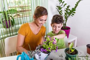 mamá y niño plantando las plantas juntos, mamá asistente de jardinero, cuidando niños y flores. chico lindo cuidar árboles y plantas, niño mojado foto