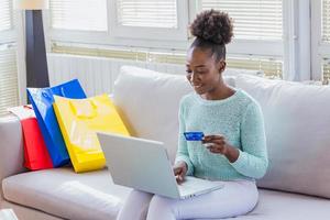 Young woman holding credit card and using laptop computer. Online shopping concept. Beautiful black girl holding credit card and using laptop. photo