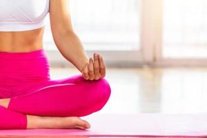Young attractive smiling woman practicing yoga, sitting in Half Lotus exercise, Ardha Padmasana pose, wearing sportswear, meditation session, indoor full length, home interior, work out from home photo