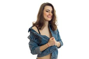 una joven encantadora con chaqueta de jeans mira a la cámara y sonríe foto