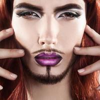 Cute charming male model with magenta makeup looking at camera photo