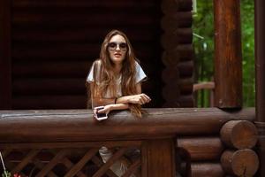 sexy lady in sunglasses at the wooden house posing photo