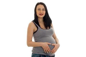 a young pregnant woman holding up hands for the stomach isolated on white background photo