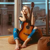 Woman with beautiful smile looking at the camera and hugging a guitar photo