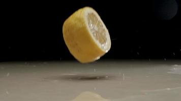 Fresh sliced lemon falling and splashing on water at slow motion video