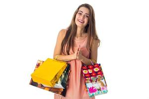Una joven divertida tiene muchos paquetes de compras brillantes aislados de fondo blanco foto