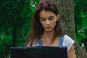 a close-up portrait of young beautiful brunette who looks in a laptop photo