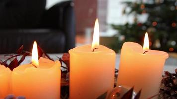 quatre bougies allumées sur une guirlande de noël qui brillent d'une ambiance romantique à la veille sainte et aux vacances de noël devant un arbre de noël décoré de fête comme symbole chrétien traditionnel de l'avent video