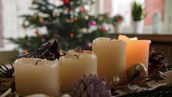después de las vacaciones de navidad, la corona de navidad con sus cuatro velas de adviento encendidas se apaga y deja velas humeantes debajo del árbol de navidad después de la víspera santa en la celebración festiva a la luz de las velas video