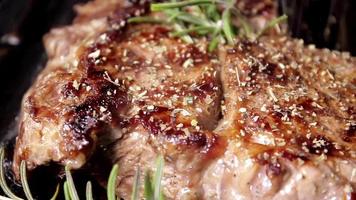 Grilling beaf steak. Cooking and pouring rosemary flavour on meat. Delicious beef food preparation. video