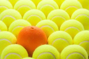 Group of Tennis Balls and One Orange photo