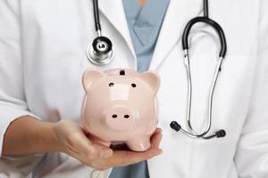 Doctor with Stethoscope Holding Piggy Bank Abstract photo