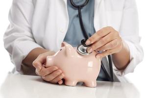 Doctor Holding Stethoscope to Piggy Bank photo