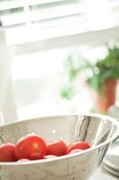 tomates roma frescos y vibrantes en colador con gotas de agua foto