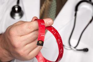 Doctor with Stethoscope Holding Measuring Tape photo