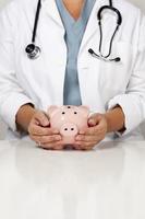 Doctor with Caring Hands on a Piggy Bank photo