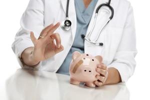 Doctor Gives Okay Sign Behind Piggy Bank photo