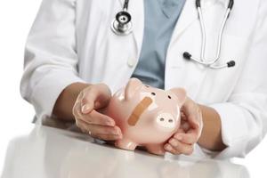 Doctor Holding Caring Hands on a Piggy Bank with Bandage photo