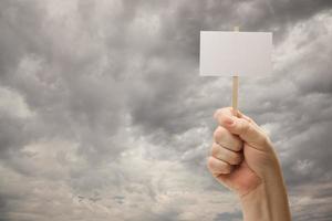 hombre que sostiene un cartel en blanco sobre nubes de tormenta dramáticas foto