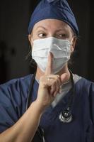 Secretive Female Doctor with Finger in Front of Mouth photo