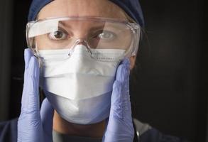 doctora o enfermera poniéndose ropa protectora facial foto