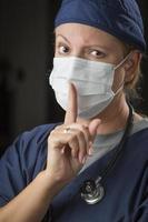 Secretive Female Doctor with Finger in Front of Mouth photo