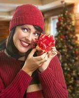 mujer sosteniendo un regalo envuelto en un entorno navideño foto