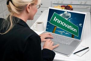 mujer en la cocina usando una laptop con un signo de innovación foto