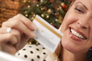 Phone Holding Woman Credit Card In Front of Christmas Tree photo