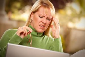 mujer haciendo muecas usando una laptop que sufre dolor de cabeza foto