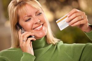Cheerful Woman Using Her Phone with Credit Card photo