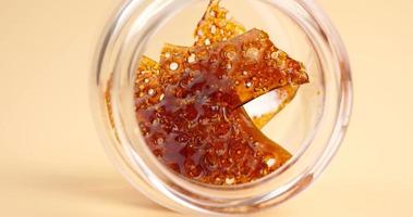 glass jar with brown cannabis wax, pieces of hardened resin of marijuana extract video