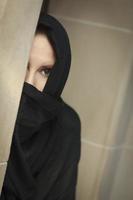 mujer islámica cautelosa en el panel de la ventana usando burka o niqab foto