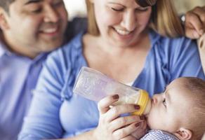 Happy Mixed Race Couple Bottle Feeding Their Son photo