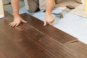 hombre instalando nuevos pisos de madera laminada foto