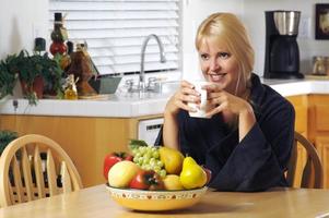Woman with Cup of Coffee in Kitchen Smiling photo